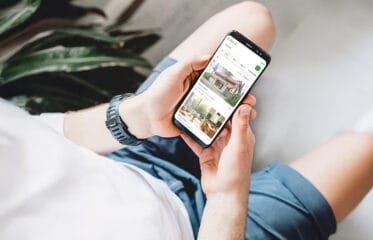 Person browsing rental listings on mobile, comparing property prices and photos to choose a rental home